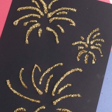 Gold glitter fireworks on black paper.
