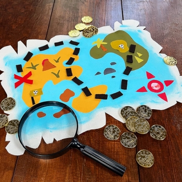 DIY scrap fabric adventure map with magnifying glass and plastic gold coins.