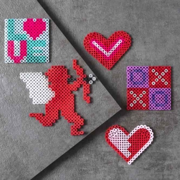 Perler beads in Valentine's Day designs (Cupid, hearts, Love word, and XOXO).