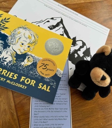 The book Blueberries for Sal with a coloring page, a stuffed black bear, and a bookmark with suggested discussion questions.