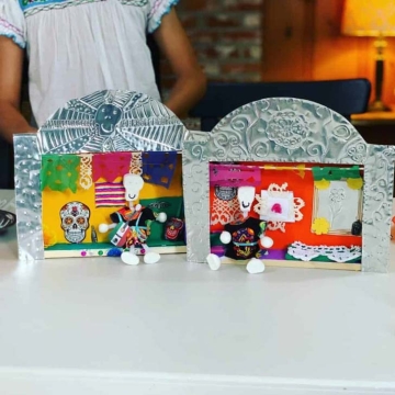 Homemade decorated miniature nicho boxes with clay calacas and Mexican-themed embellishments in them.